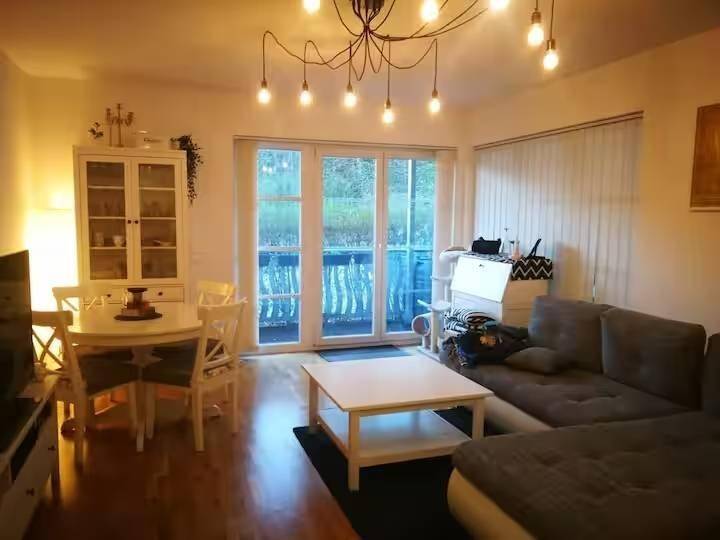 Gemütlicher Wohn-Essbereich mit Sofa, Esstisch und Zugang zu einem Balkon.