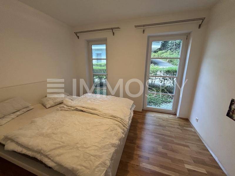 Helles Schlafzimmer mit Holzboden und Zugang zu einem kleinen Außenbereich mit Bepflanzung.