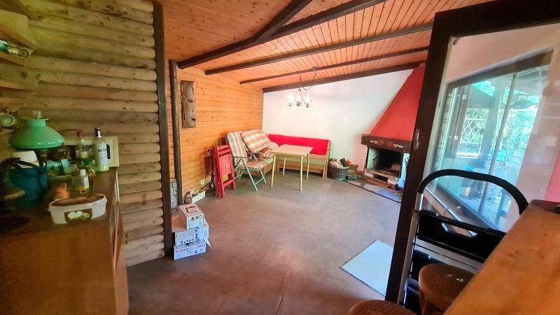 Rustikales Wohnzimmer mit Holzwänden, Holzbalkendecke und einem gemütlichen Kamin.