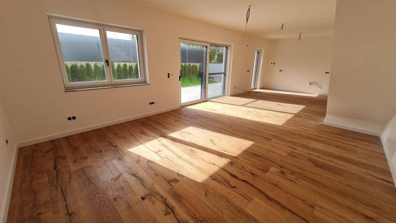 Lichtdurchfluteter Wohnbereich mit großen Fenstern und elegantem Holzplankenboden.