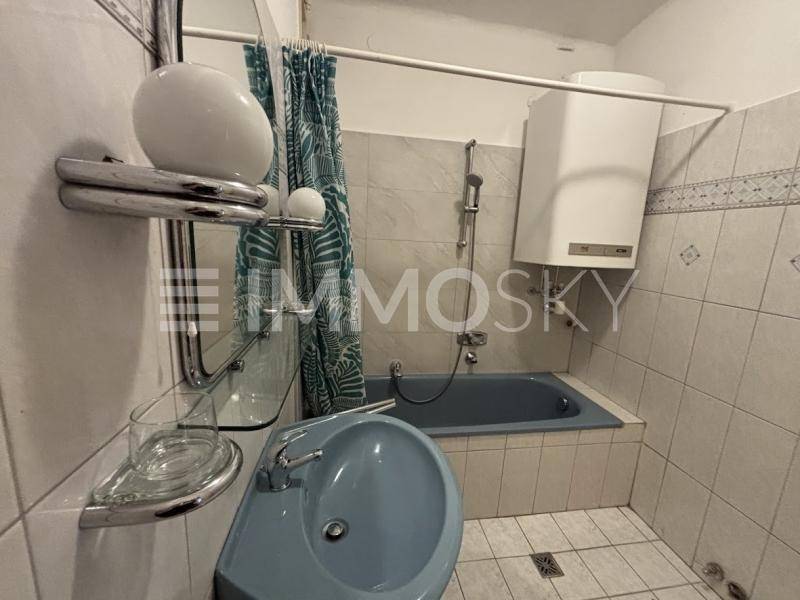 Badezimmer mit blauer Badewanne, passendem Waschbecken und Wandfliesen im 80er-Jahre-Stil.