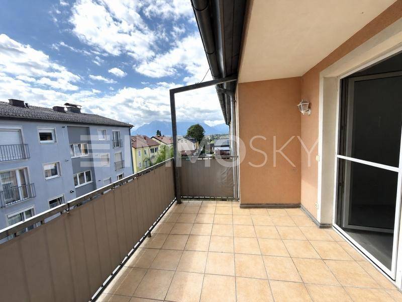 Geräumiger Balkon mit Fliesenboden und einem weiten Blick über die Stadt und die umliegenden Berge.