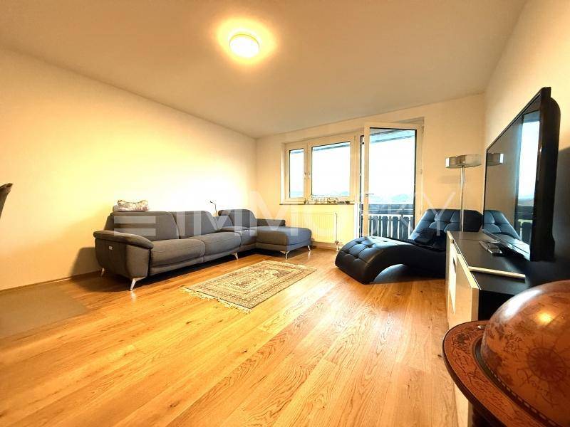 Gemütliches Wohnzimmer mit modernem Sofa, Holzboden und Zugang zu einem Balkon.