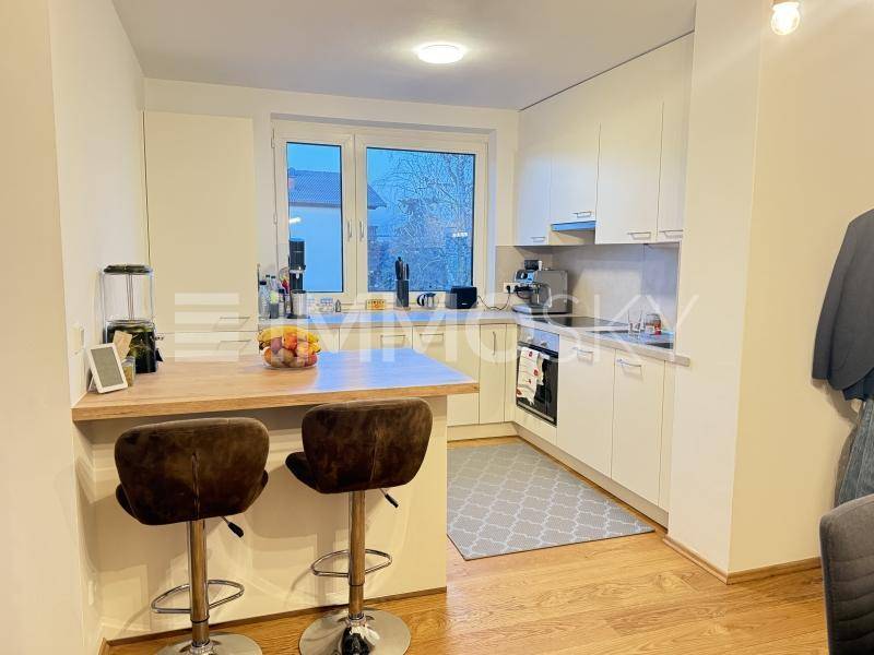 Moderne Küche mit weißen Schränken, Holzarbeitsplatte, Frühstücksbar und Fenster.