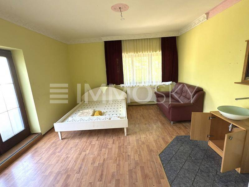 Helles Schlafzimmer mit Holzboden, Bettgestell und integriertem Waschbeckenbereich.