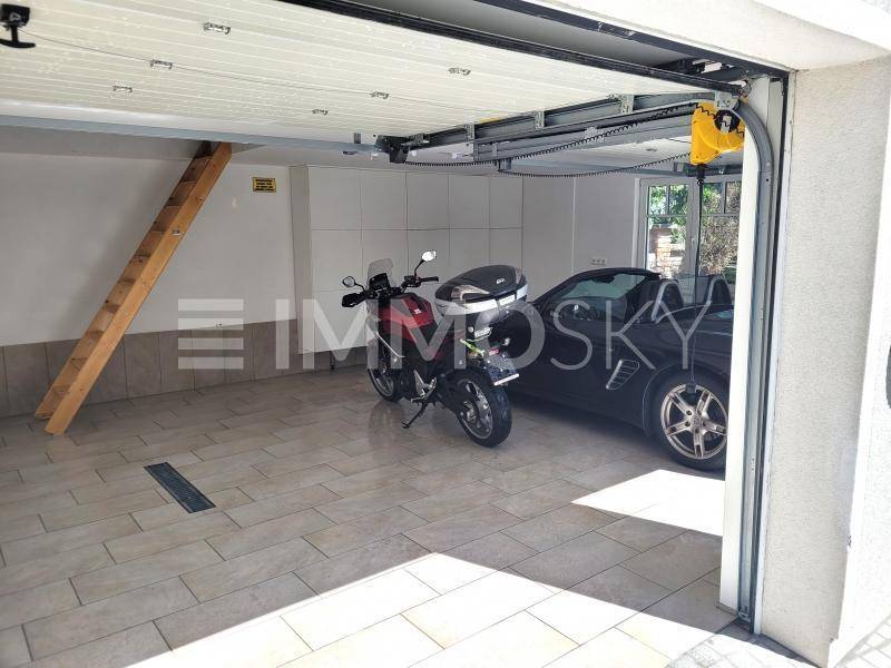 Geräumige Garage mit Fliesenboden, Stauraum und Platz für Auto sowie Motorrad.