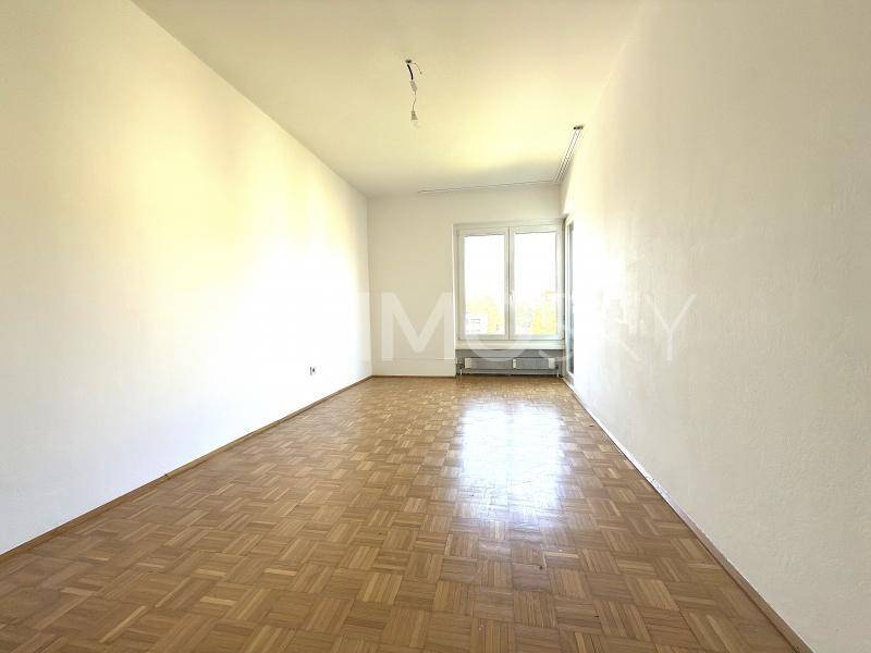Geräumiges, leeres Zimmer mit klassischem Parkettboden und hellen Wänden, bereit zur individuellen Gestaltung.