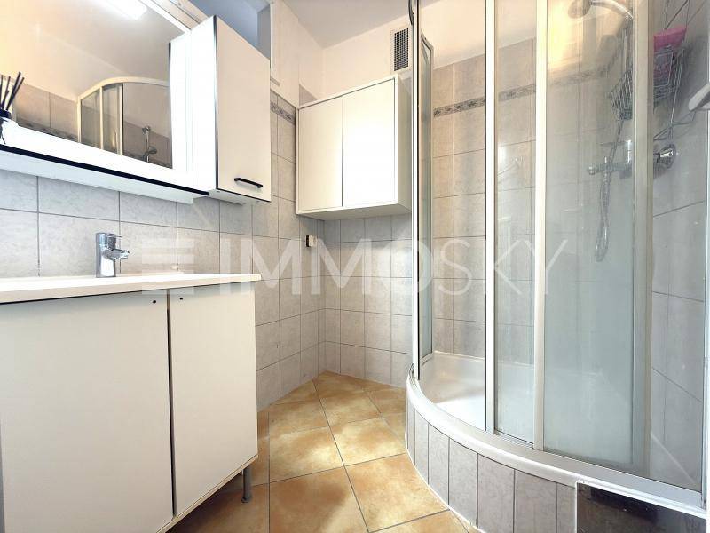 Gefliestes Badezimmer mit Duschkabine, Waschbeckenunterschrank und Spiegelschrank.