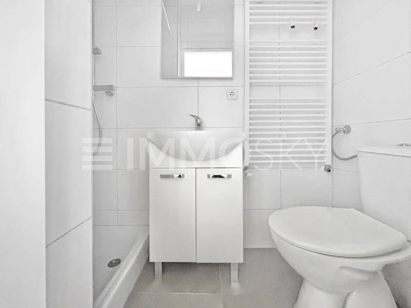 Modernes Badezimmer mit Dusche, Waschbecken, Toilette und beheiztem Handtuchhalter.