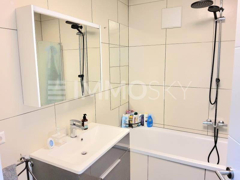 Modernes Badezimmer mit Badewanne, Duschfunktion, Waschbecken und Spiegelschrank.