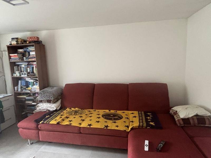 Gemütliches Wohnzimmer mit rotem Ecksofa, Bücherregal und heller Wandgestaltung.