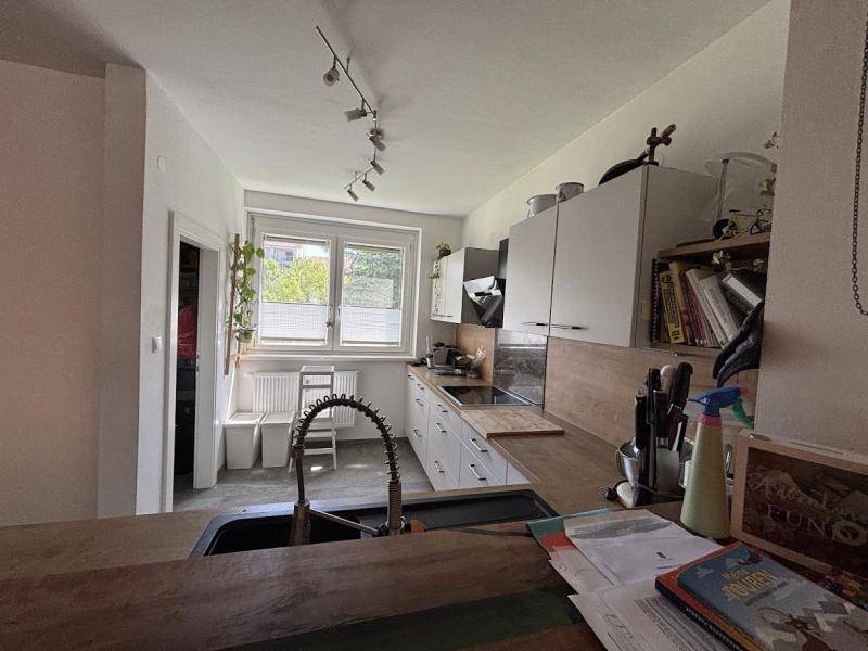 Funktionale Küche mit weißen Schränken, Holzarbeitsplatten und einem Fenster für Tageslicht.