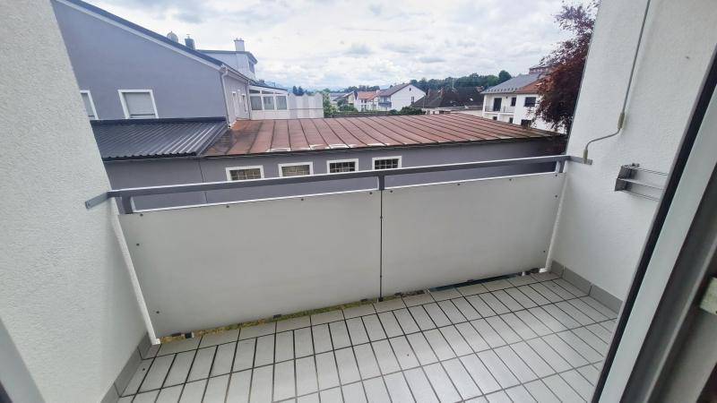 Balkon mit Fliesenboden und Blick auf die umliegenden Dächer und Gebäude.