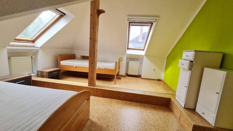 Schlafzimmer im Dachgeschoss mit zwei Betten, Dachfenstern und Holzbalken.