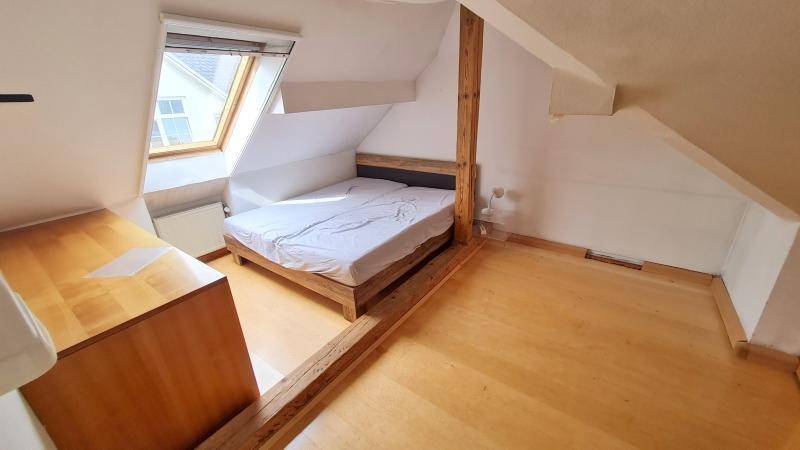 Gemütliches Schlafzimmer im Dachgeschoss mit Holzbett, Dachschräge und Dachfenster.