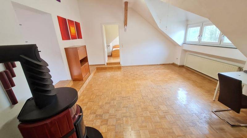 Helles Wohnzimmer im Dachgeschoss mit Parkettboden, Kaminofen und Dachschrägen.