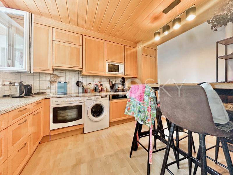 Funktionale Küche mit Holzschränken, integrierten Geräten und einer praktischen Frühstücksbar mit Hockern.