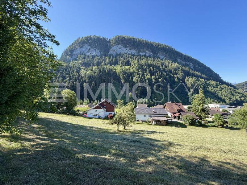 Panoramablick auf die umliegende Berglandschaft mit bewaldeten Hängen und vereinzelten Häusern in der Ferne.