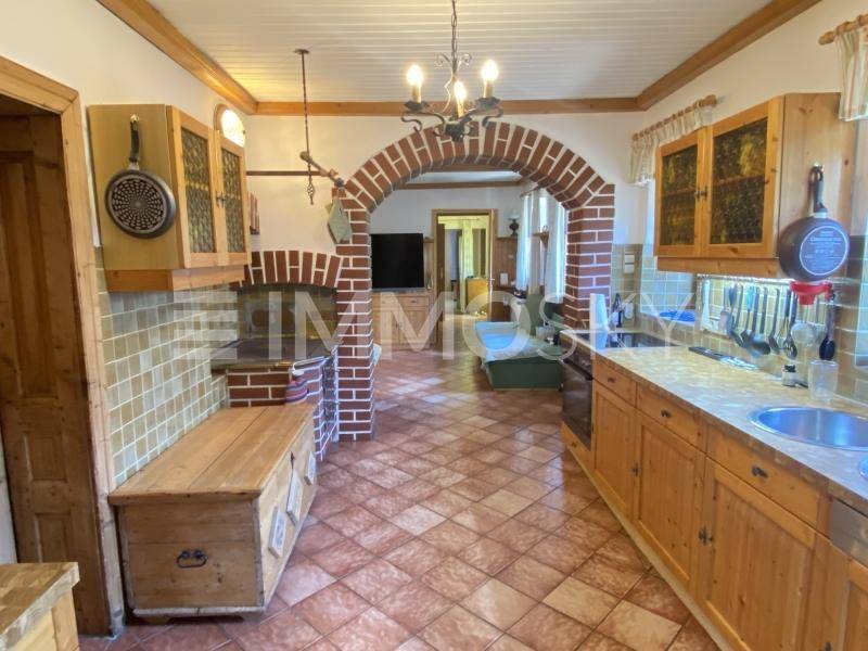 Traditionelle Küche mit Terrakottafliesen, Holzschränken und einem markanten Ziegelbogen.