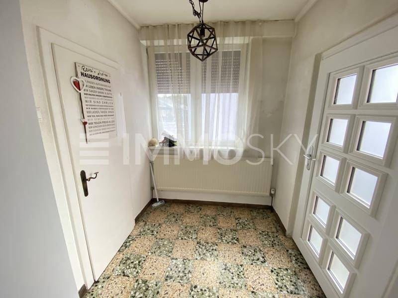 Heller Eingangsbereich mit gemusterten Fliesen, Fenster und Heizkörper.