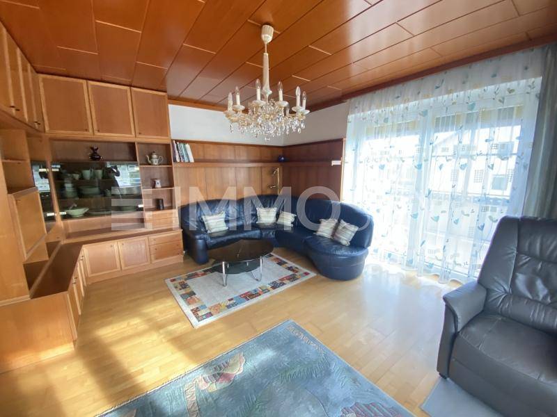 Gemütliches Wohnzimmer mit Holzdecke, Parkettboden, großem Sofa und viel Tageslicht.