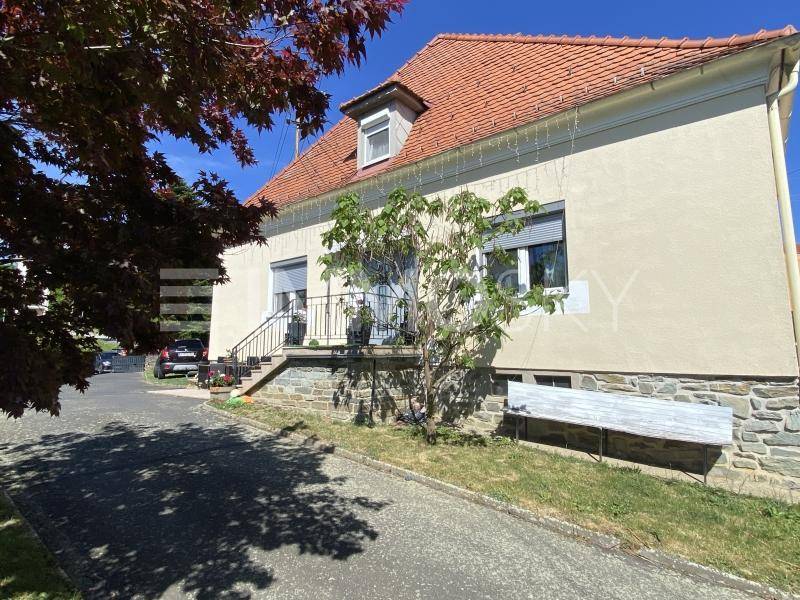 Vorderansicht des Hauses mit gepflegter Fassade, Fenstern mit Rollläden und Zufahrt.
