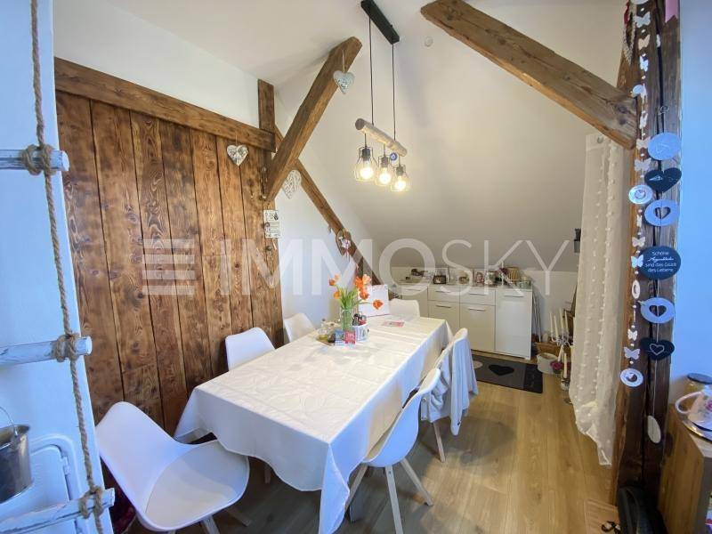 Rustikaler Essbereich im Dachgeschoss mit Holzbalken, Holzwand und modernem Esstisch.