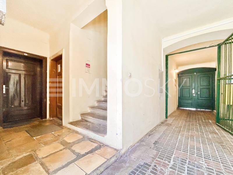 Geräumiger Eingangsbereich mit Steinfliesen, Treppe und Zugang zum Innenhof.