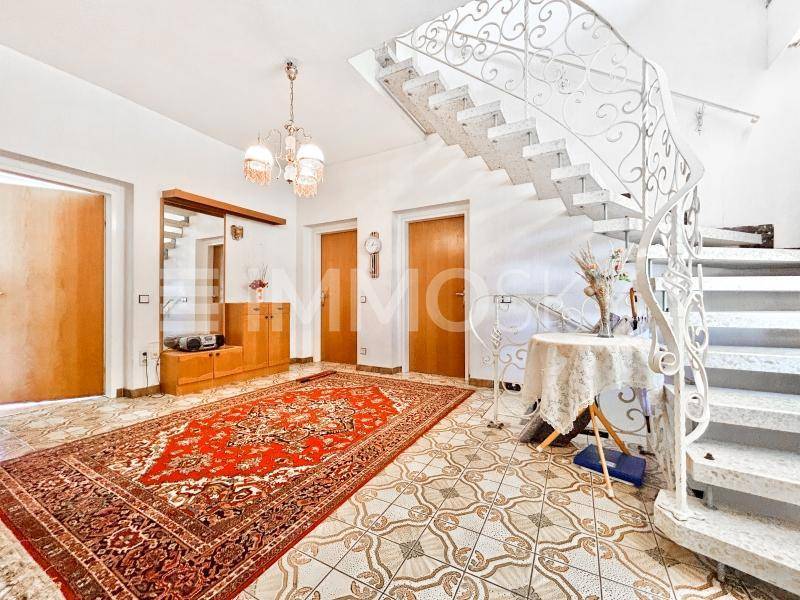 Geräumiger Eingangsbereich mit eleganter Marmortreppe, gemusterten Fliesen und traditionellem Teppich.