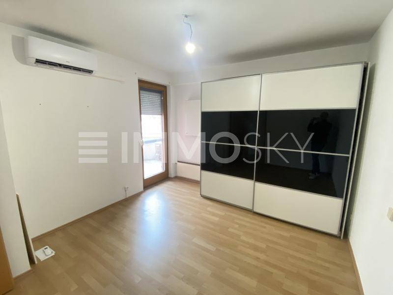 Schlafzimmer mit großem Schiebetürenschrank, Klimaanlage und Zugang zu einem Balkon.
