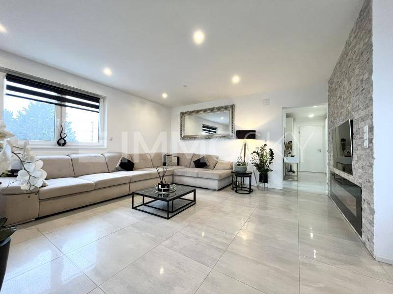 Helles Wohnzimmer mit großem Ecksofa, modernen Fliesen und dekorativer Steinwand mit Kamin.