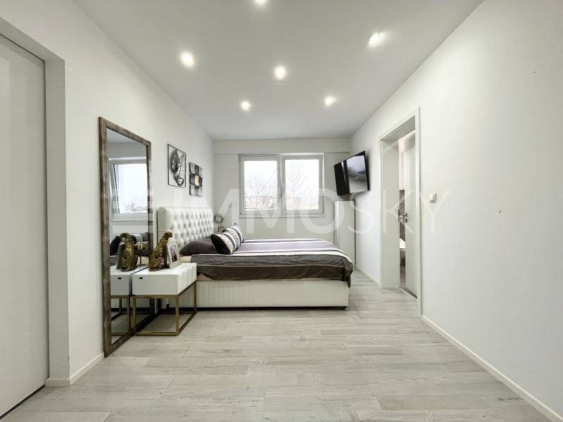 Modernes Schlafzimmer mit großem Bett, Spiegel und hellem Fliesenboden.