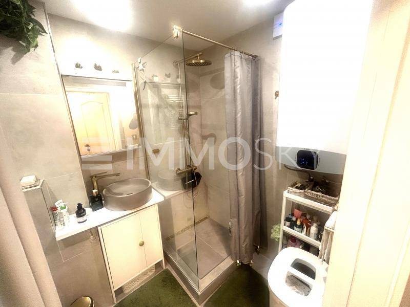 Modernes Badezimmer mit Duschkabine, runder Waschschale und goldenen Armaturen.