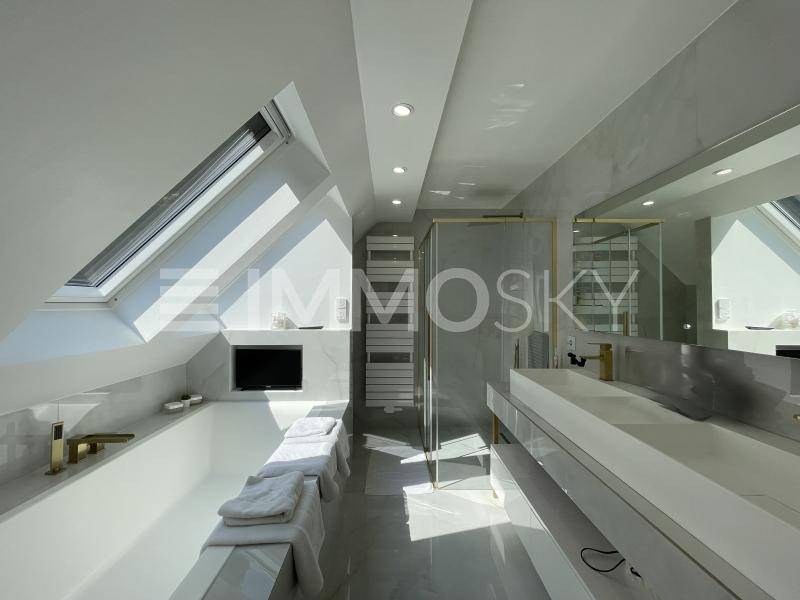 Luxuriöses Badezimmer im Dachgeschoss mit Badewanne, Dusche, Doppelwaschbecken und Dachfenstern.