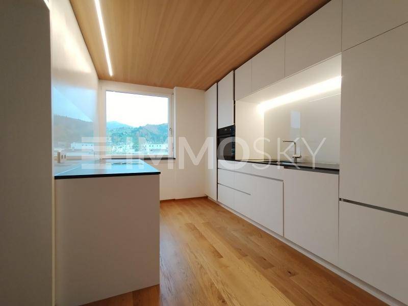 Moderne Einbauküche mit weißen Fronten, Holzboden und integrierten Geräten.