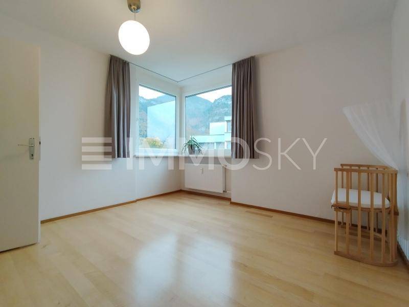 Lichtdurchflutetes Schlafzimmer mit Parkettboden, Erkerfenster und Platz für ein Kinderbett.