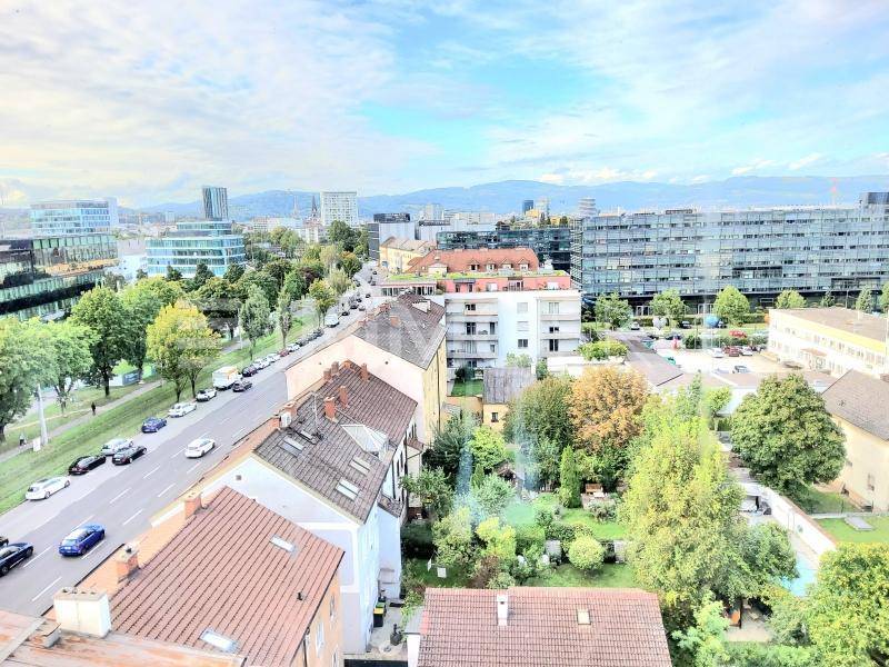 Weitläufiger Blick über die Stadt mit Wohngebäuden, Geschäftsstraßen und grünen Flächen.