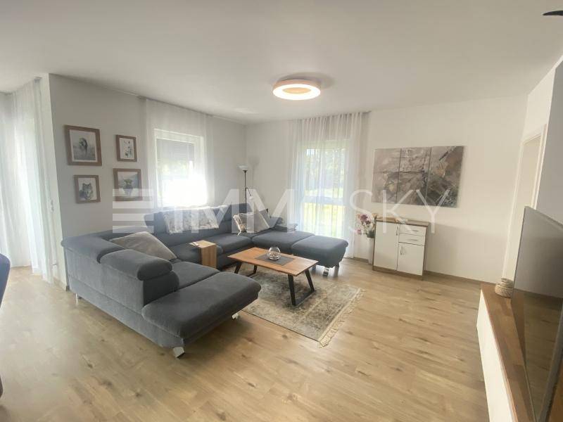 Gemütliches Wohnzimmer mit großem Ecksofa, hellem Holzboden und viel Tageslicht.