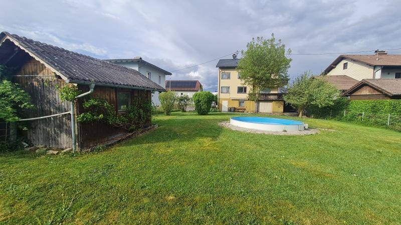 Großer grüner Garten mit einem Aufstellpool und einem Holzschuppen, im Hintergrund das Wohnhaus.