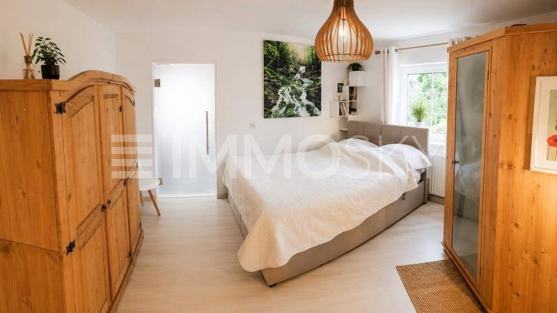 Helles Schlafzimmer mit Holzbett, passenden Kleiderschränken und natürlichem Lichteinfall durch das Fenster.