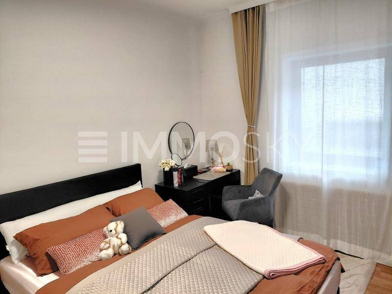 Helles Schlafzimmer mit Doppelbett, Nachttisch und großem Fenster für viel Tageslicht.