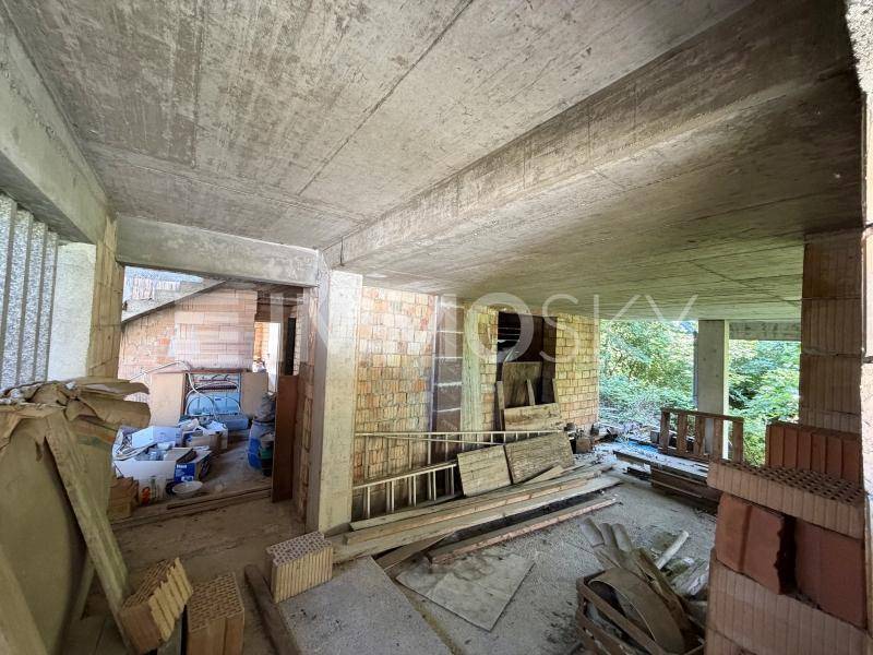 Innenansicht eines Rohbaus mit unverputzten Ziegelwänden, Betonböden und Decken, bereit für den Ausbau.
