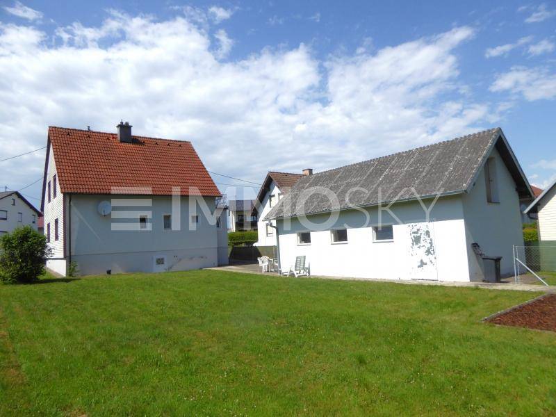 Großer Gartenbereich mit Rasenfläche, dem Haupthaus und einem Nebengebäude im Hintergrund.