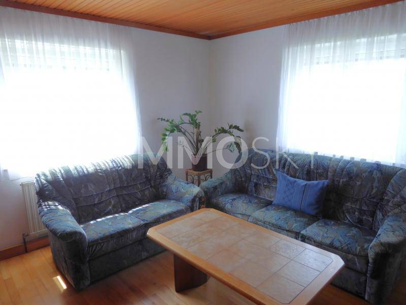 Gemütliches Wohnzimmer mit zwei Sofas, Holzbalkendecke und hellen Fenstern.