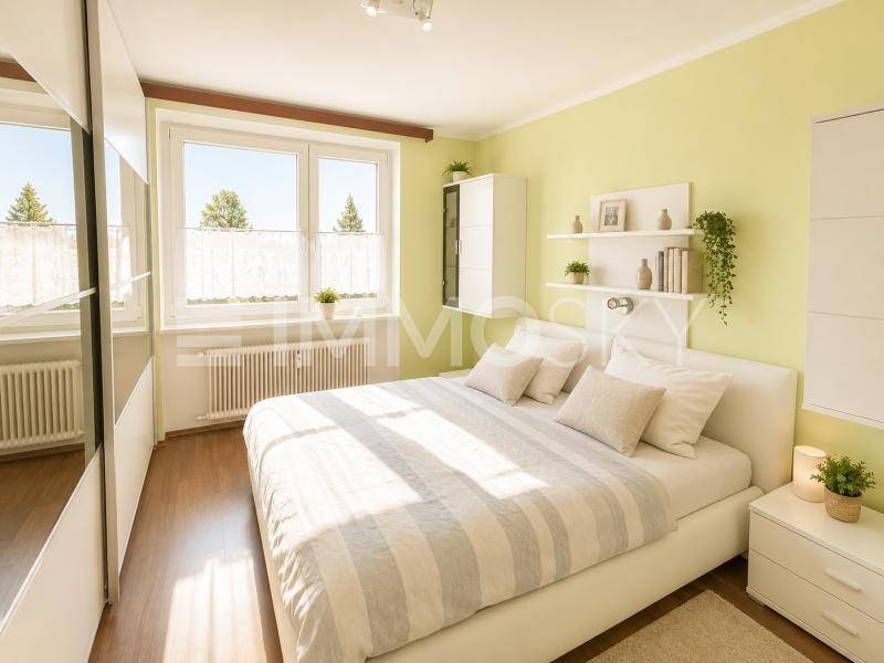 Helles Schlafzimmer mit hellgrünen Wänden, Doppelbett und großem Fenster.