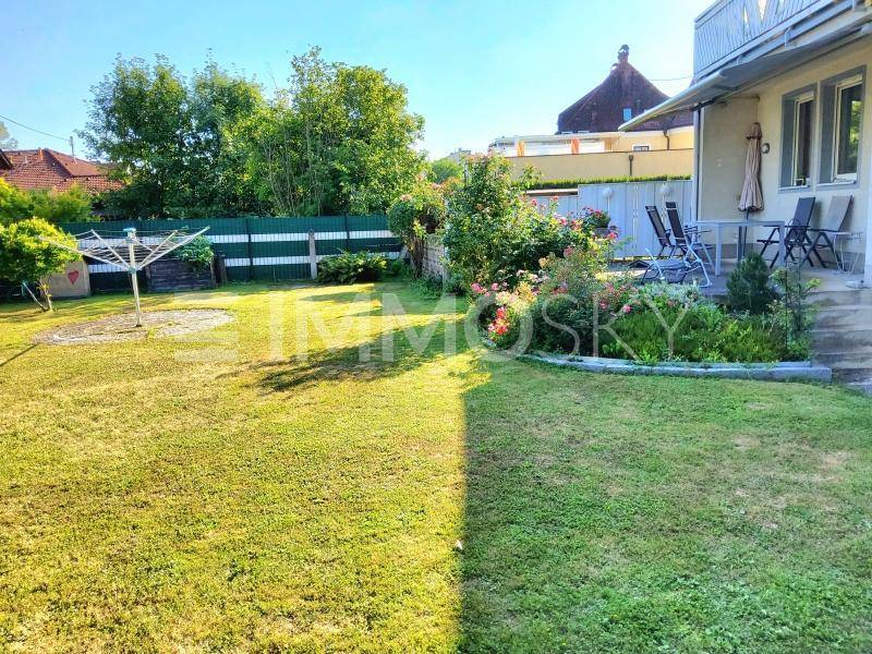 Großer, gepflegter Garten mit Rasenfläche, Blumenbeeten und Terrasse.