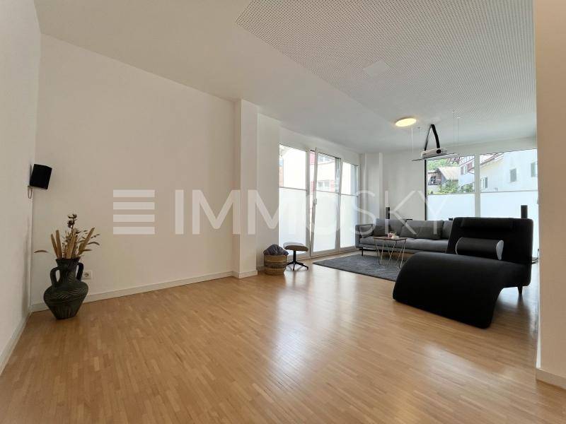 Helles Wohnzimmer mit Holzboden, großen Fenstern und moderner Einrichtung.
