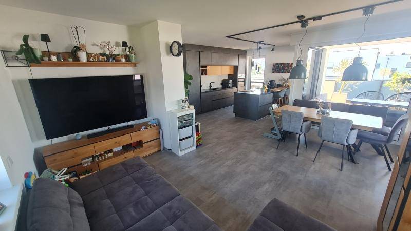 Heller, offener Wohn-Essbereich mit integrierter Küche, modernem Sofa und großem Esstisch.