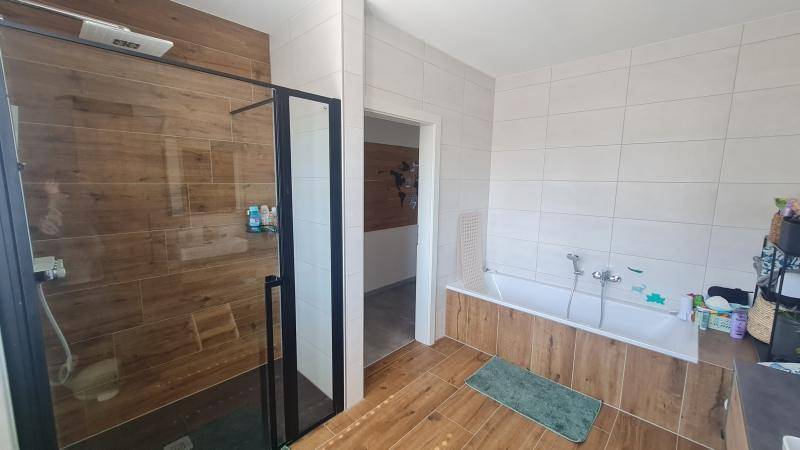 Modernes Badezimmer mit begehbarer Dusche, Badewanne und stilvollen Holzoptik-Fliesen.
