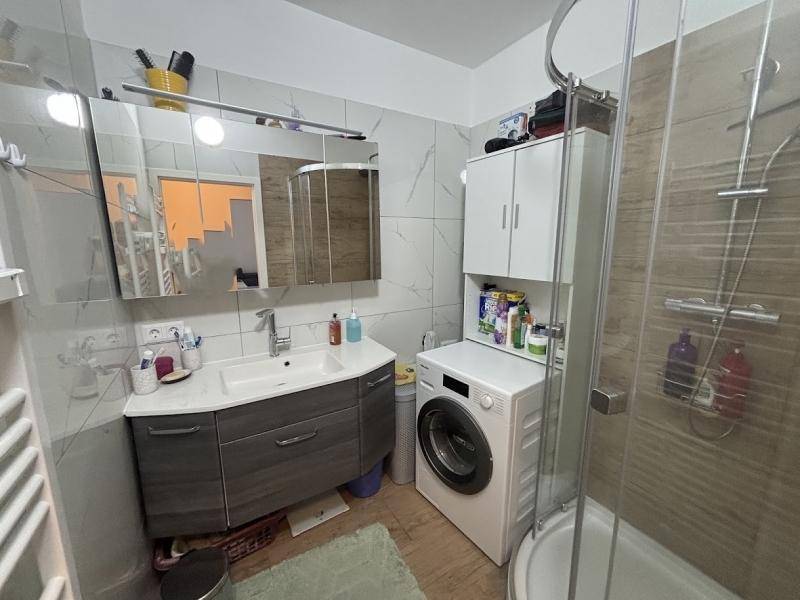 Modernes Badezimmer mit Dusche, Waschbeckenunterschrank und Waschmaschine.